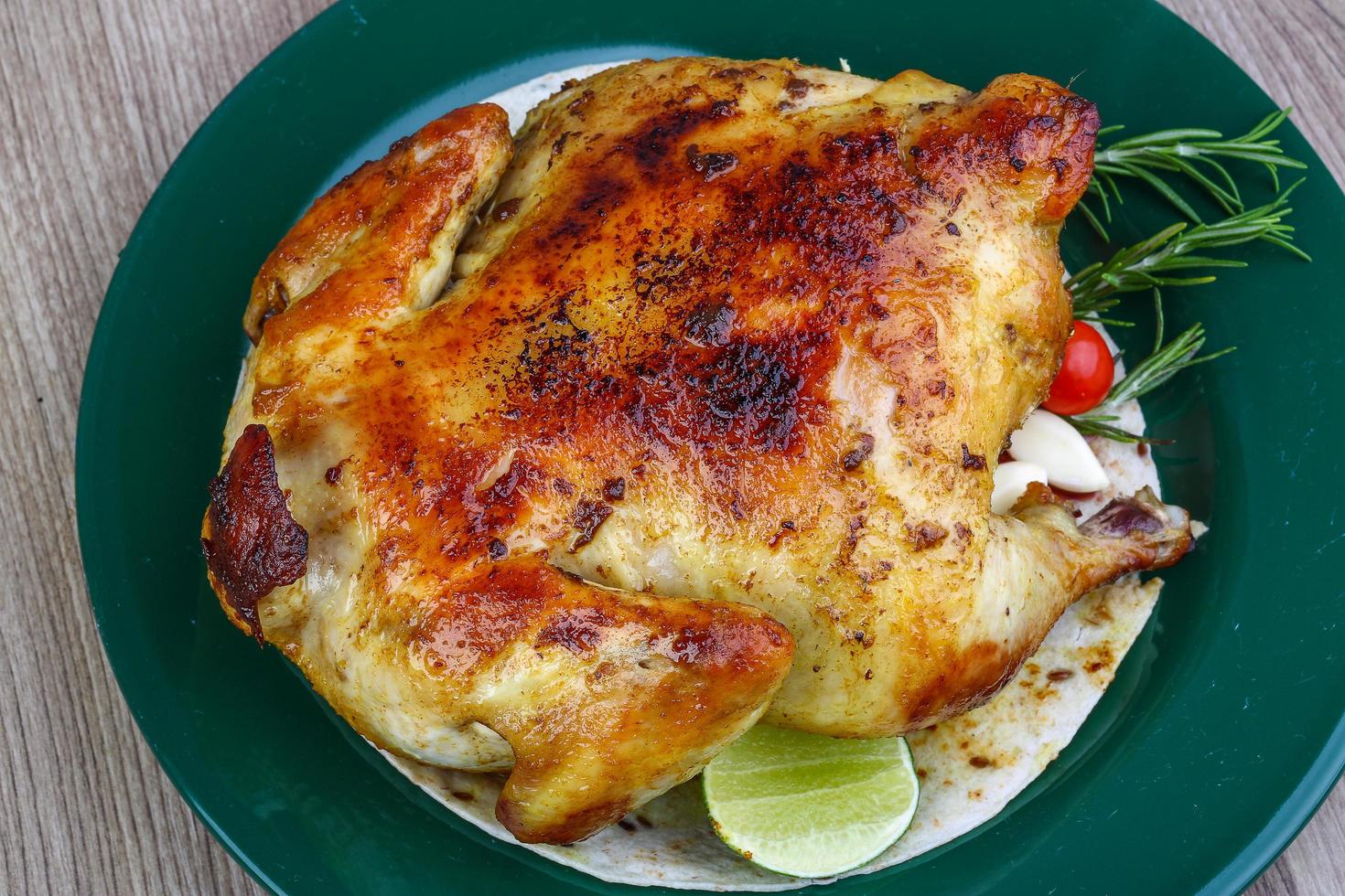 Grilled chicken on the plate and wooden background photo