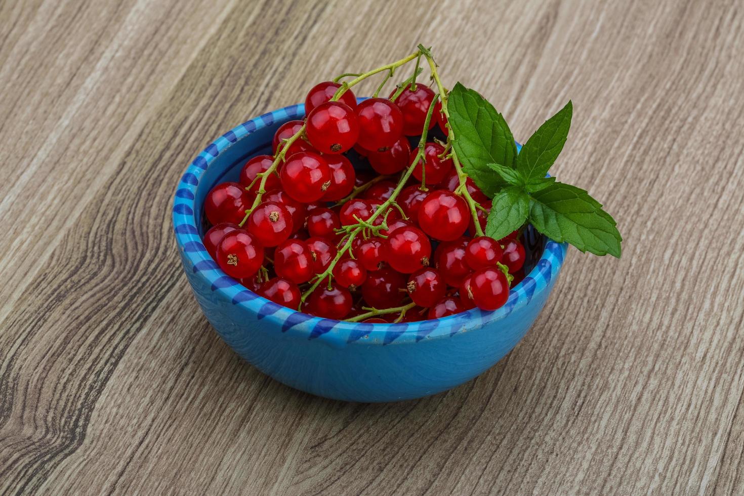 Red currants in a bowl on wooden background photo