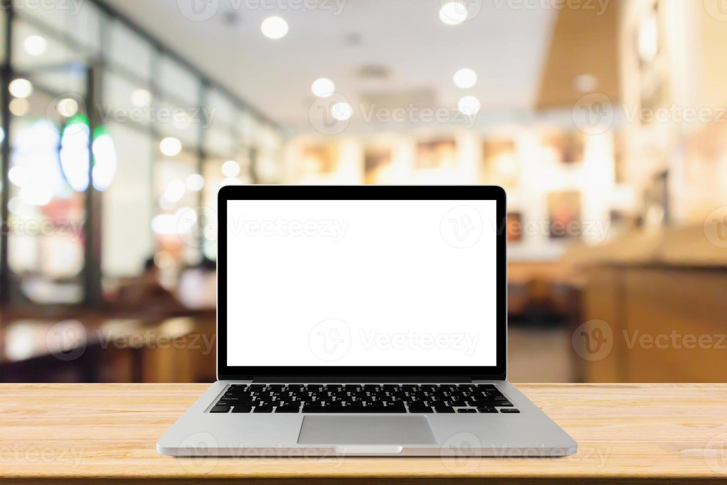 Blank screen laptop computer on wood table top with blur cafe restaurant with abstract bokeh light defocused background photo