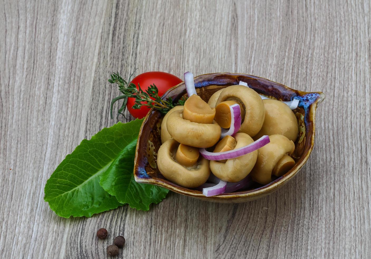 Pickled champignon in a bowl on wooden background photo