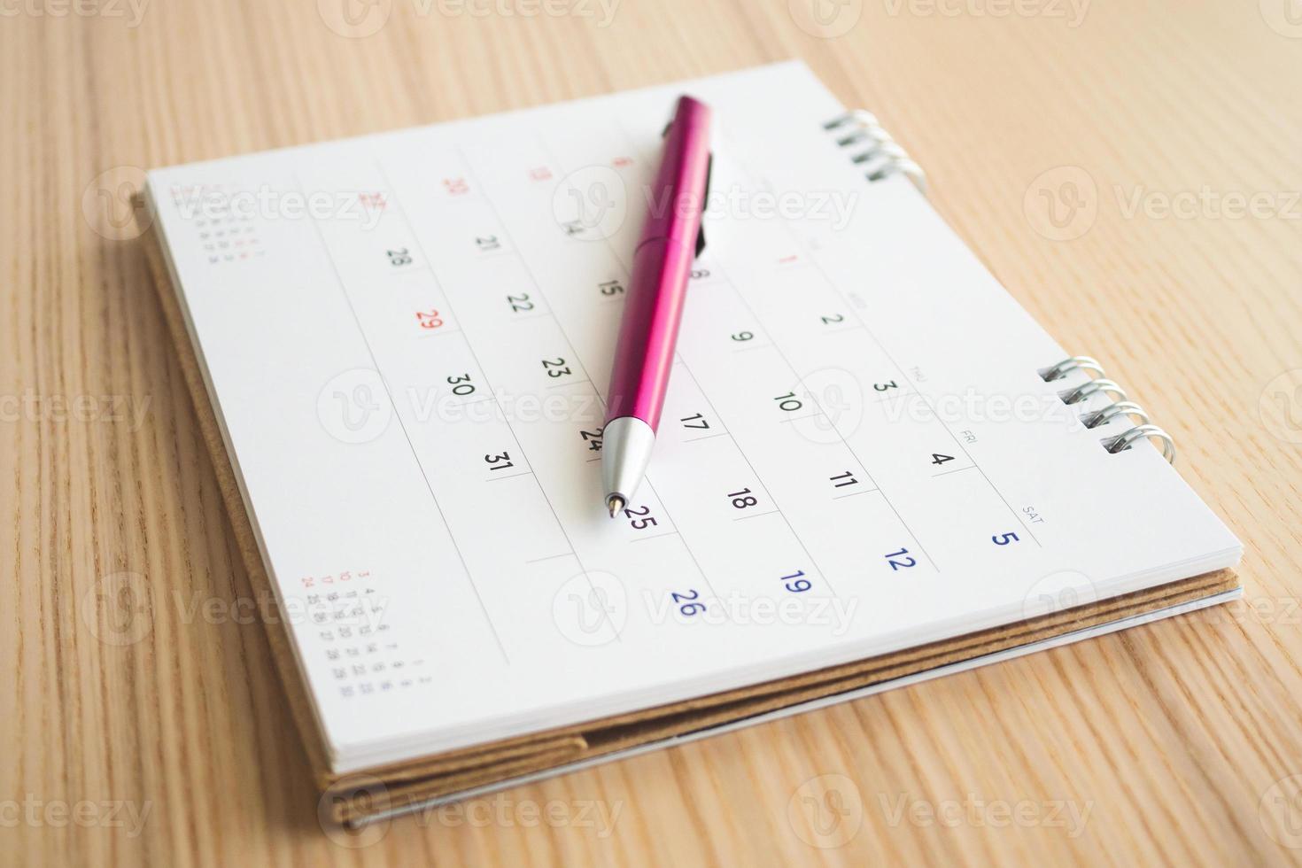 página de calendario con bolígrafo sobre fondo de mesa de madera foto