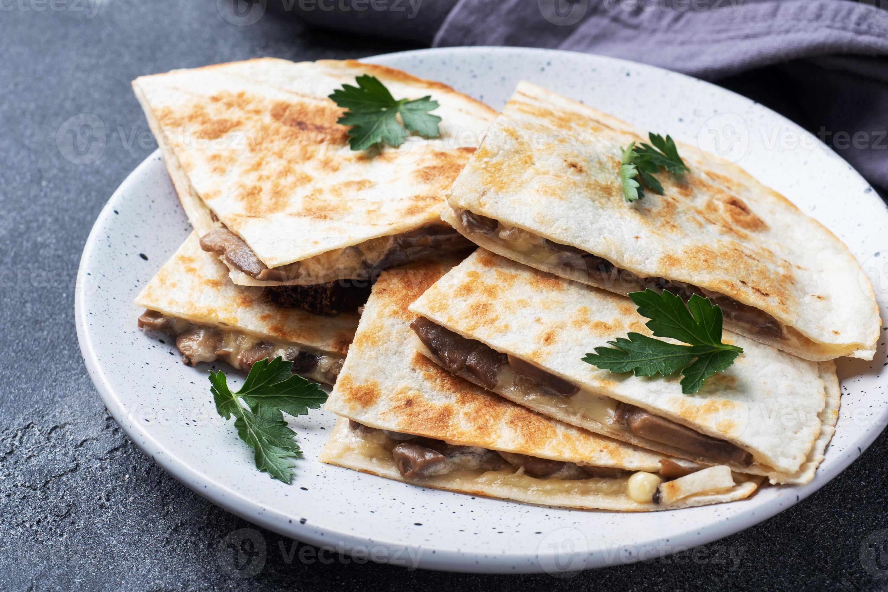 trozos de quesadilla con crema agria de champiñones y queso en un plato