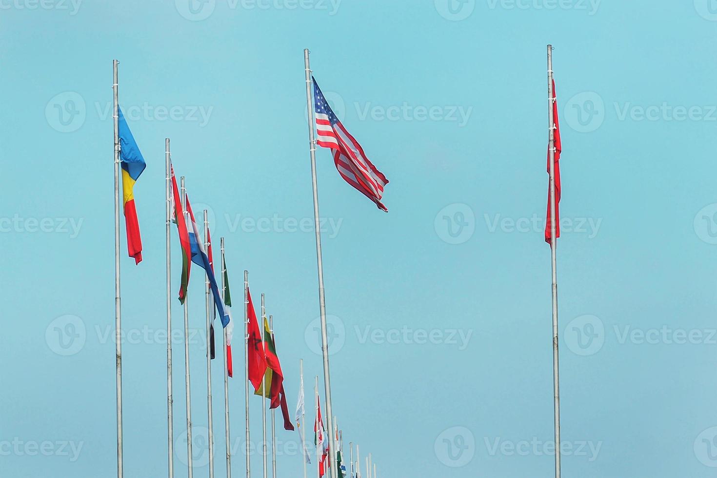 National flags of various countries flying on a blue sky. photo