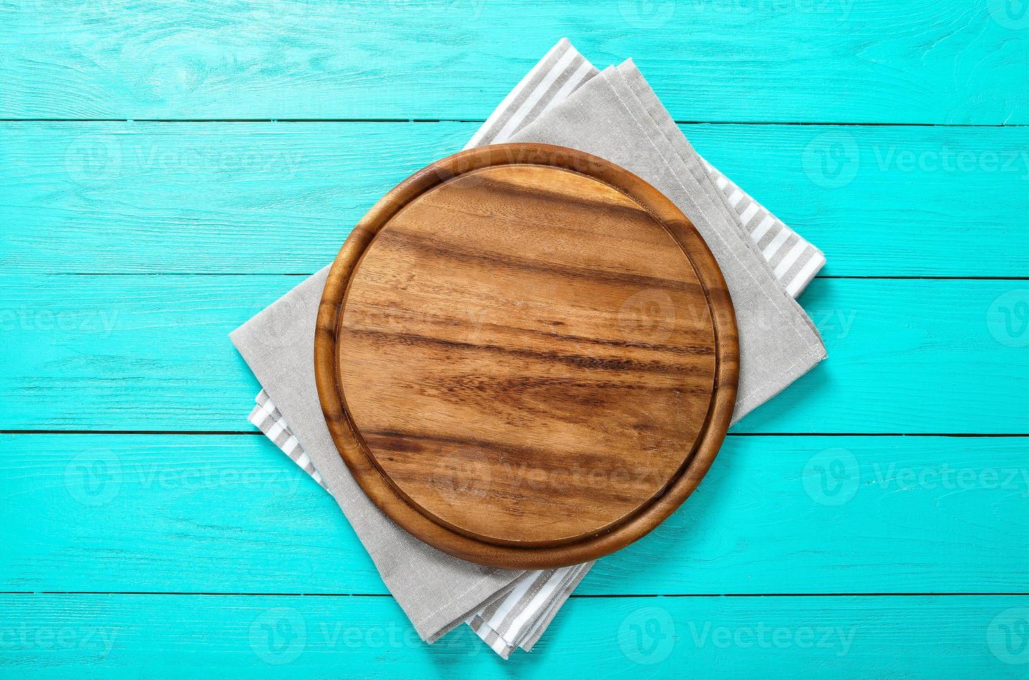 marco de tabla de cortar redonda sobre un mantel a rayas y gris sobre fondo de madera azul. vista superior y lugar para el texto foto