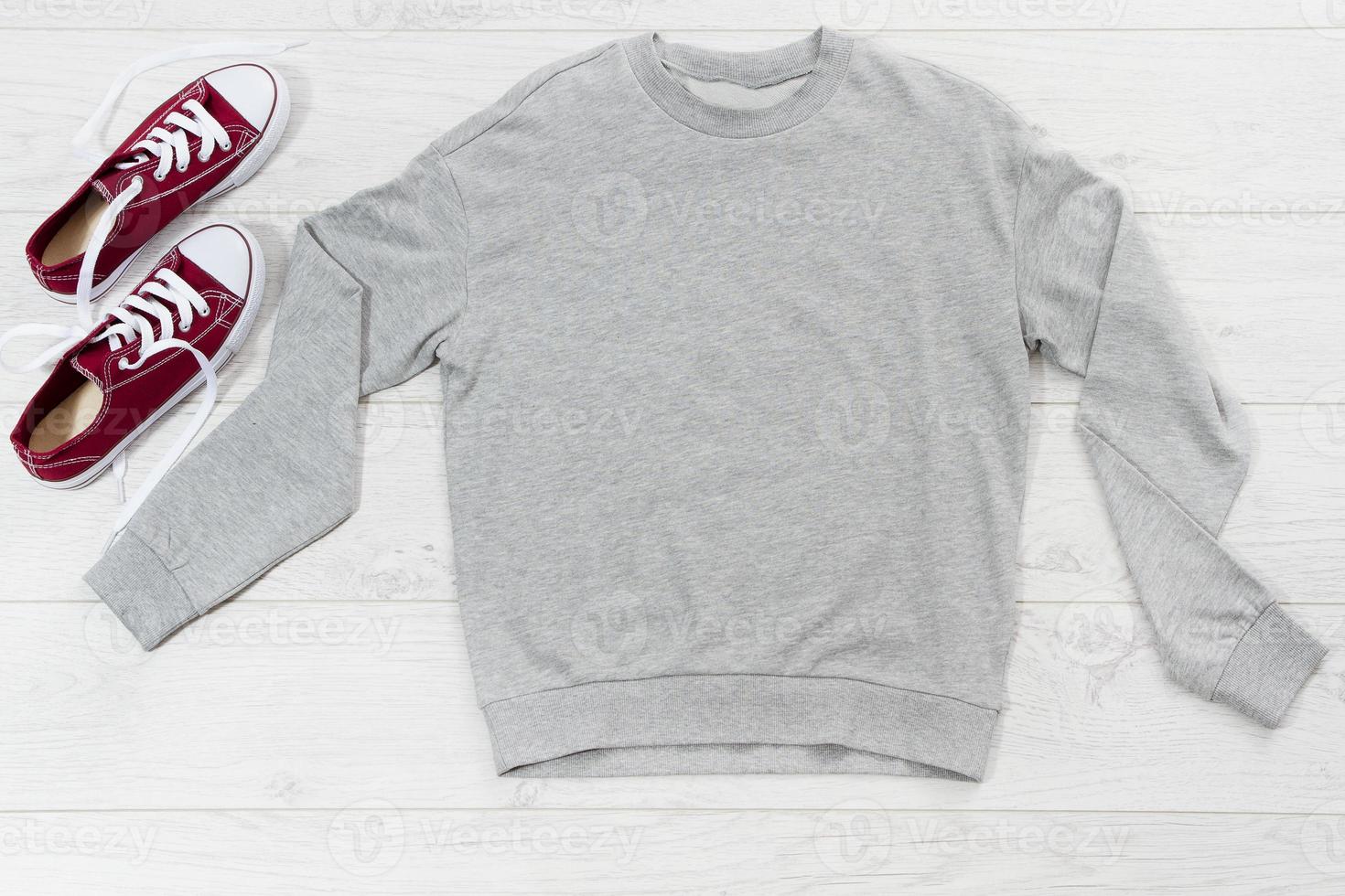Close up gray blank template sweatshirt hoodie with copy space. Top view mockup pullover on white wooden background. Casual outfit. Flat lay template clothes. photo