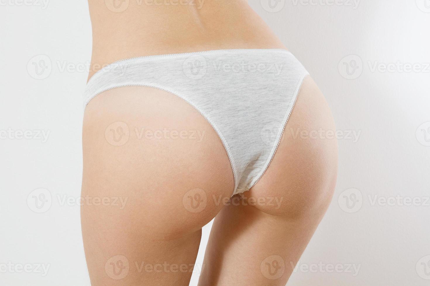 cerrar el trasero de la mujer en bragas grises aisladas. vista posterior de la ropa interior de plantilla en blanco femenino con espacio de copia y maqueta. maqueta de lencería. salud corporal, concepto de belleza. anticelulítico, afeitado línea bikini foto