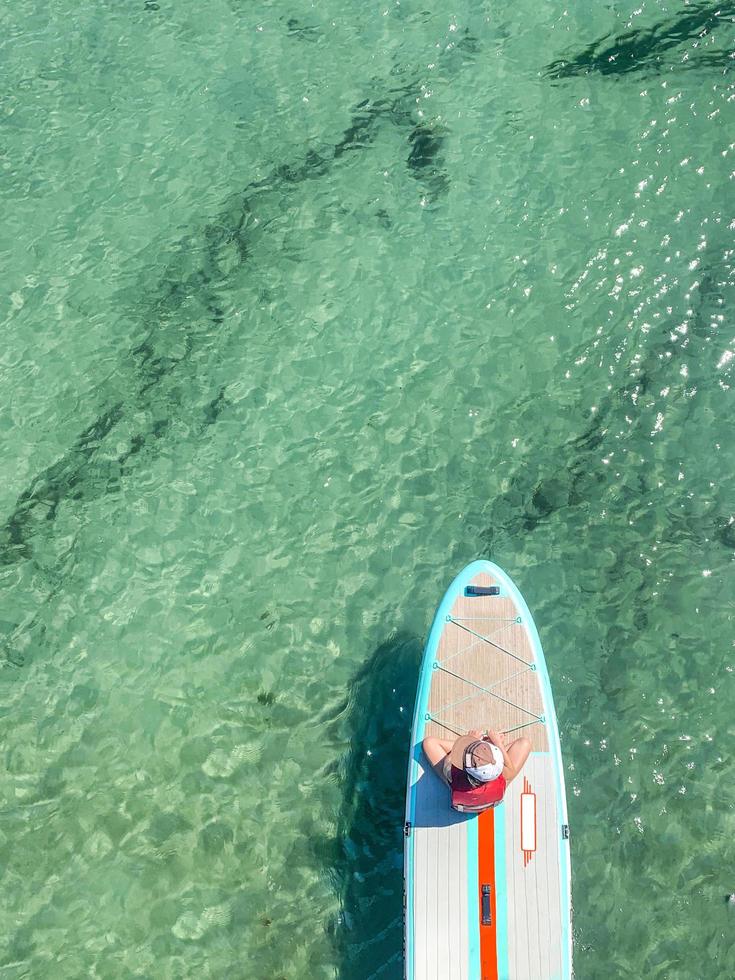 Little girl on the front of a paddle board over the ocean photo