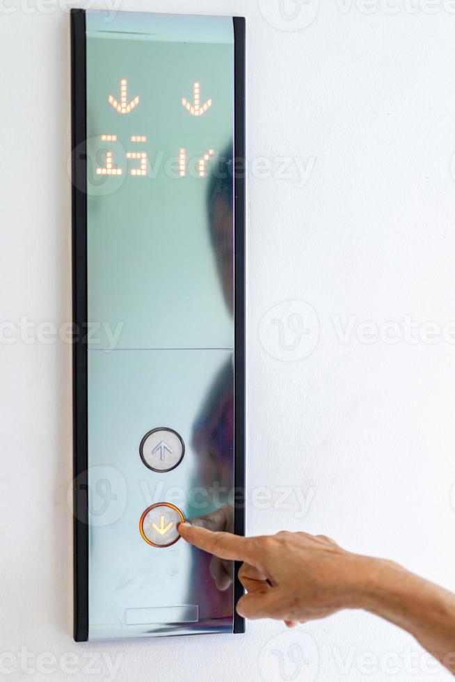 Asian old woman hand points to the button of elevator. photo