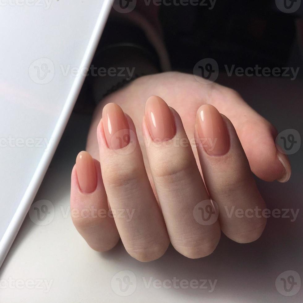 manos femeninas con elegante manicura rosa sobre fondo blanco foto