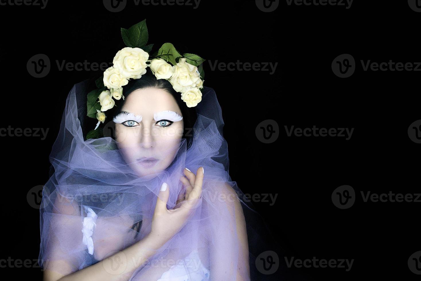 retrato conceptual de mujer extraña en corona de rosas blancas con maquillaje de fantasía para da de muertos foto