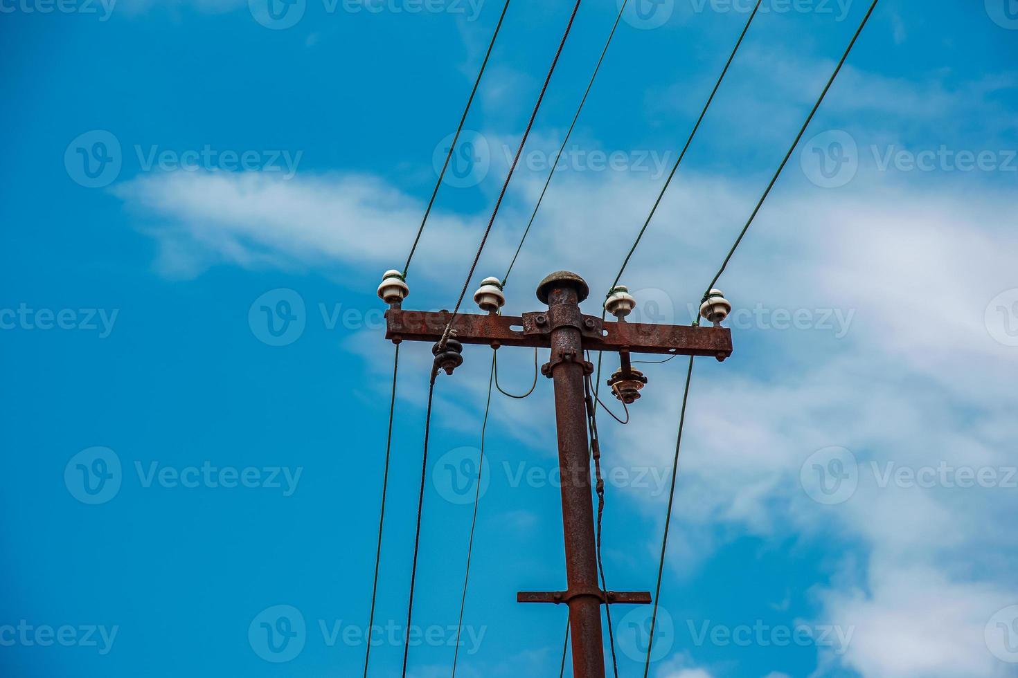 Electric pole power lines outgoing electric wires againts on cloud blue sky. photo