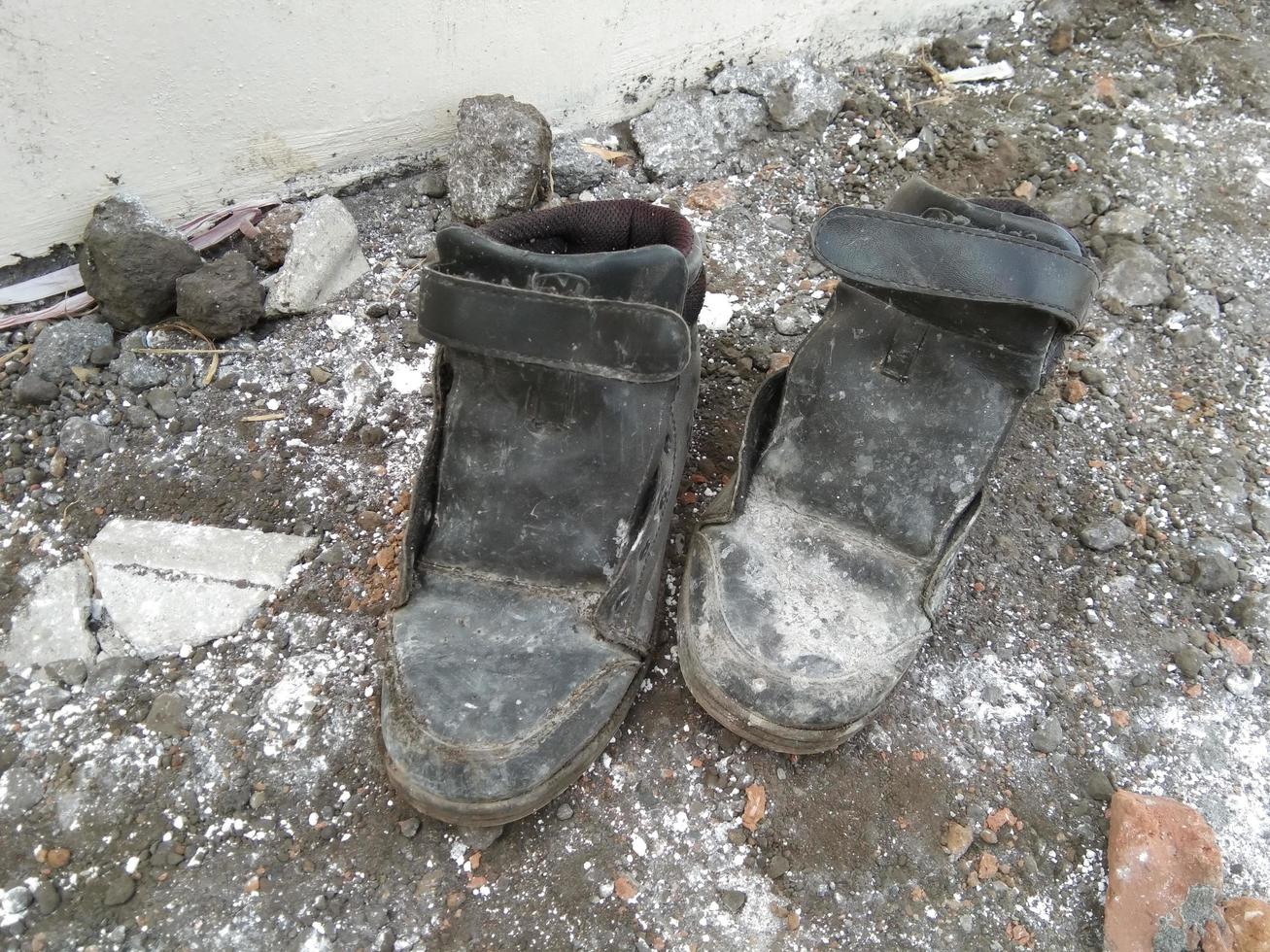 a pair of worn black shoes lying on the ground photo