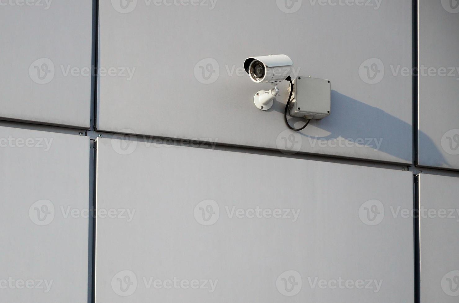 White surveillance camera built into the metal wall of the office building photo