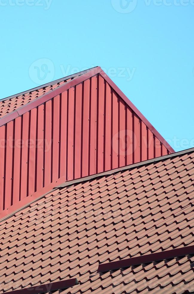 A fragment of a roof from a metal tile of dark red color. Quality Roofing photo