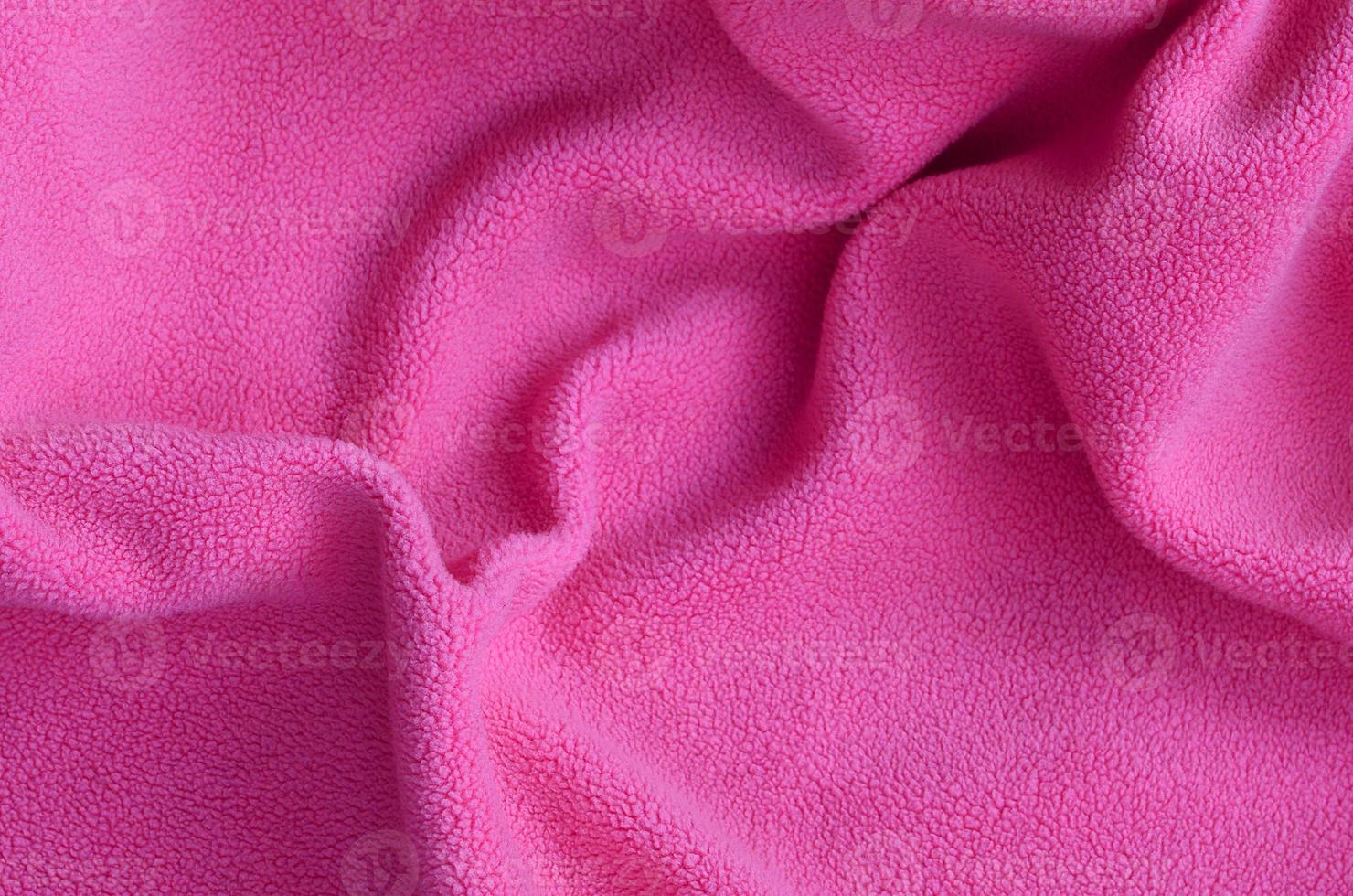 The blanket of furry pink fleece fabric. A background of light pink soft plush fleece material with a lot of relief folds photo