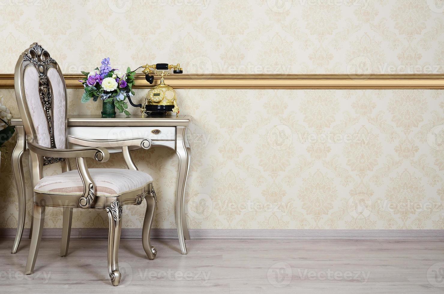 A fragment of a retro interior with a chair and a desk on which is located a telephone and a vase of flowers photo