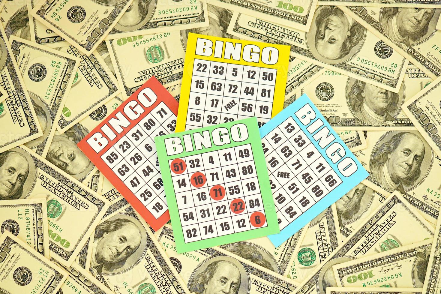 muchos tableros de bingo o naipes para ganar fichas y una gran cantidad de billetes de dólar. clásico americano o canadiense de cinco a cinco cartones de bingo en dinero foto
