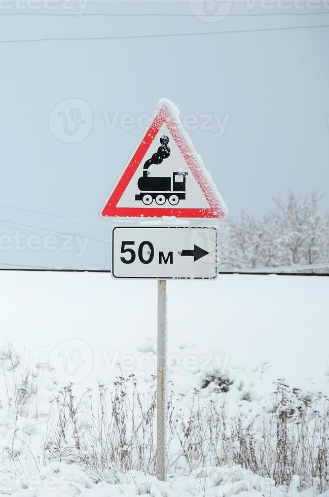 Railway crossing without barrier. A road sign depicting an old black locomotive, located in a red triangle photo