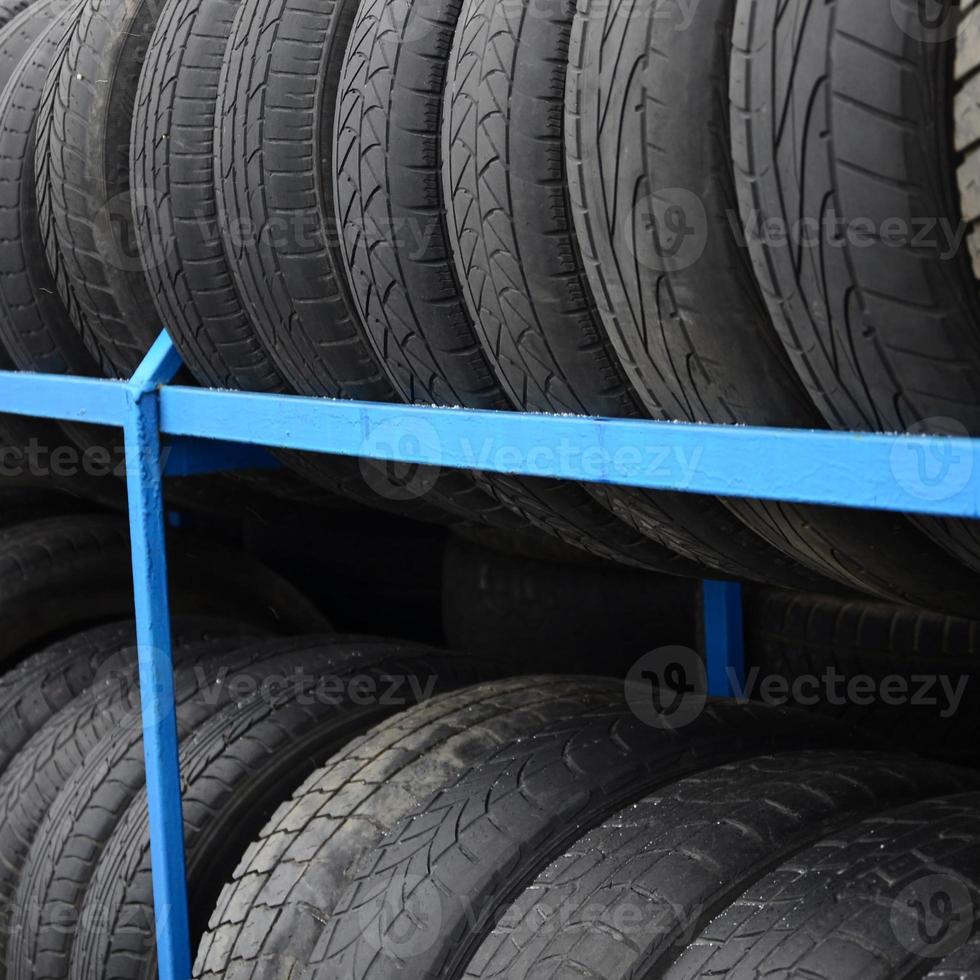 Rack with variety of car tires in automobile store. Many black tires. Tire stack background. Selective focus photo