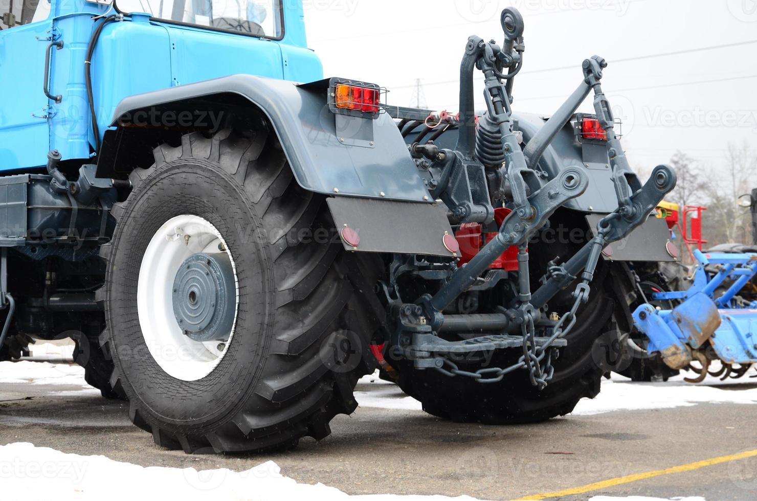 Wheels of back view of new tractor in snowy weather. Agricultural vehicle back view photo