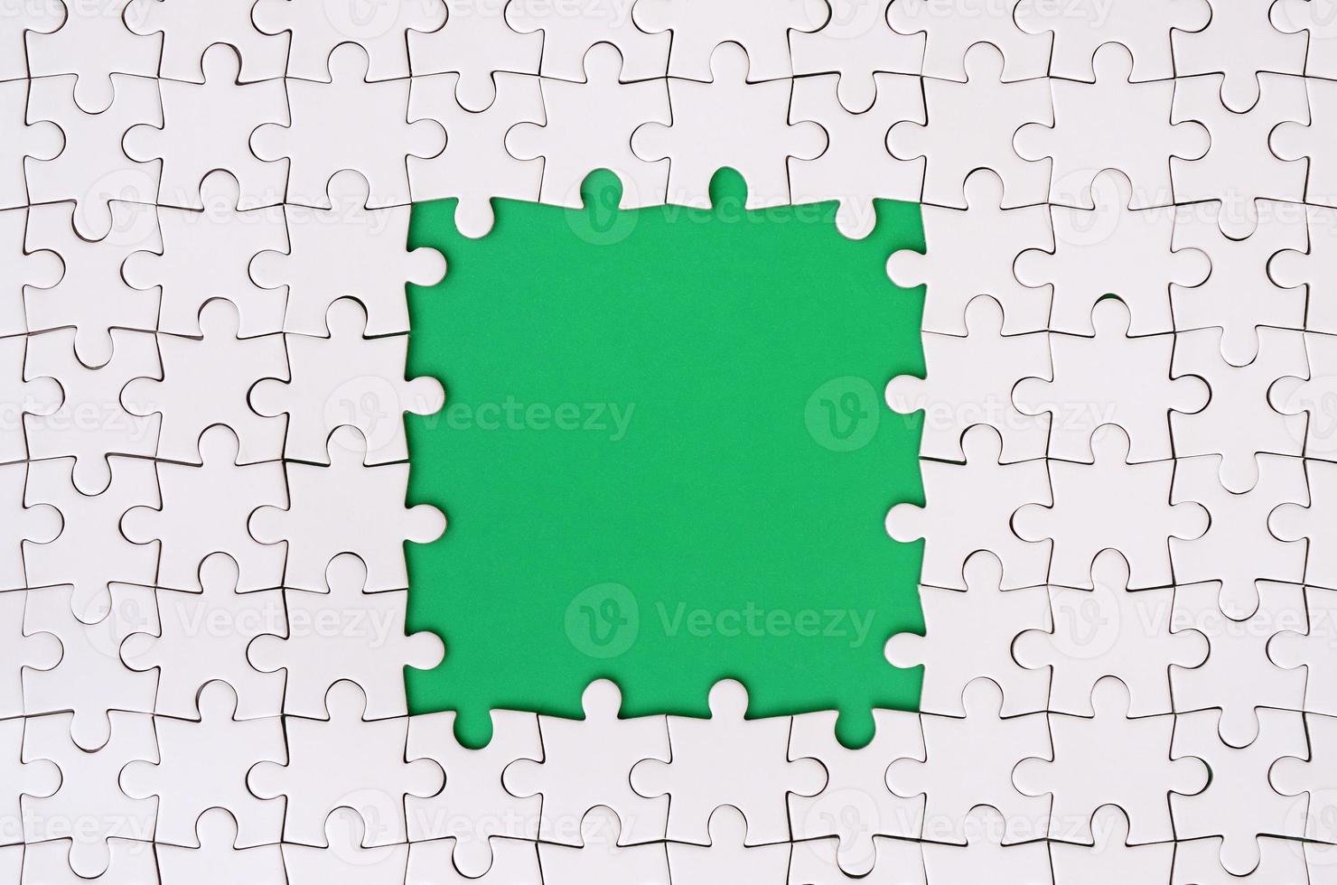 Framing in the form of a rectangle, made of a white jigsaw puzzle around the green space photo