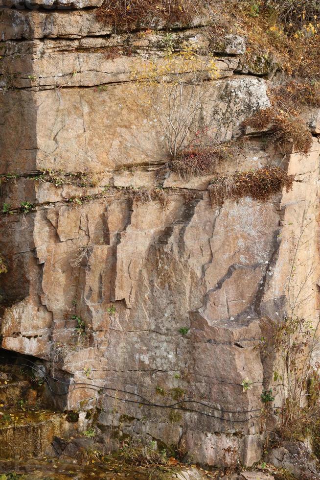 Light coarse natural rock stone background. Mining cliff rough front surface. Big limestone stack backdrop. Heavy grunge damaged granite block texture photo
