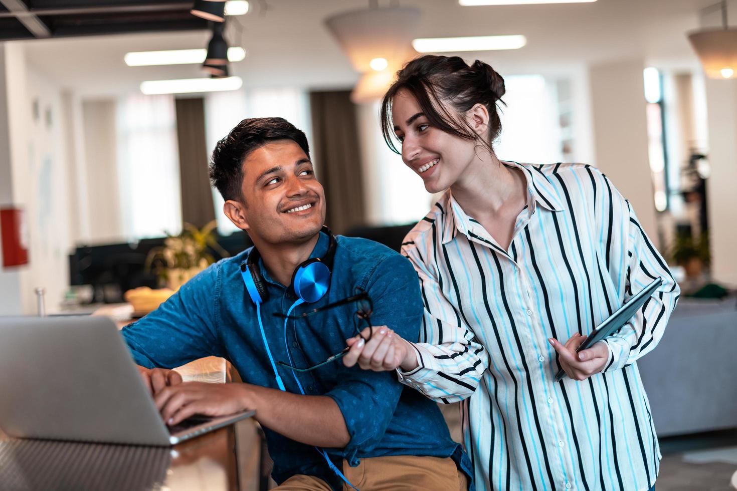 Multiethnic business people man with a female colleague working together on tablet and laptop computer in relaxation area of modern startup office photo
