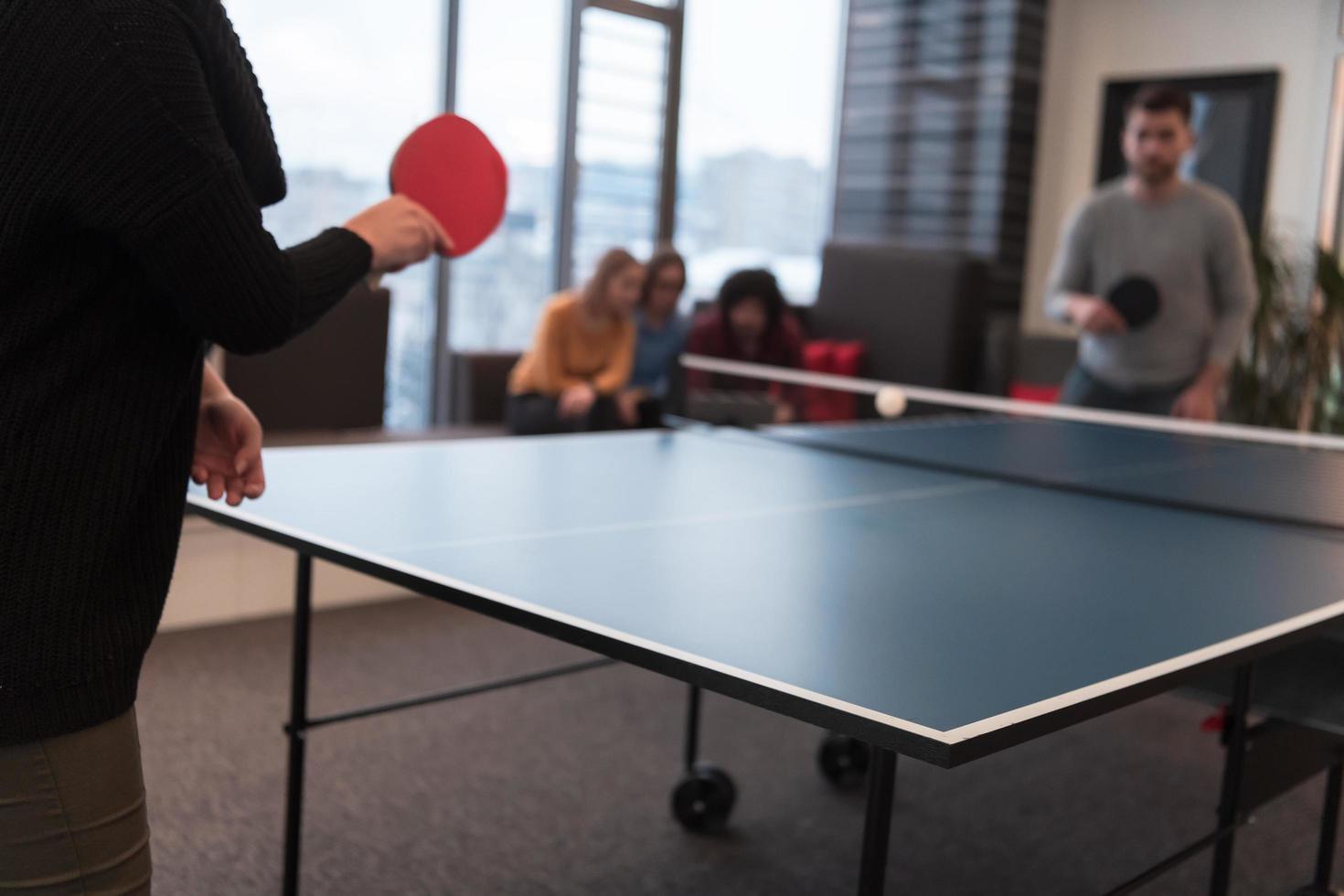 Two young start up business man playing table tennis at modern creative office space people group have meeting and brainstorming in background photo