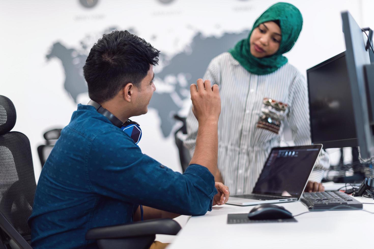 Multiethnic startup business team woman wearing a hijab on meeting in modern open plan office interior brainstorming, working on laptop and desktop computer. Selective focus photo