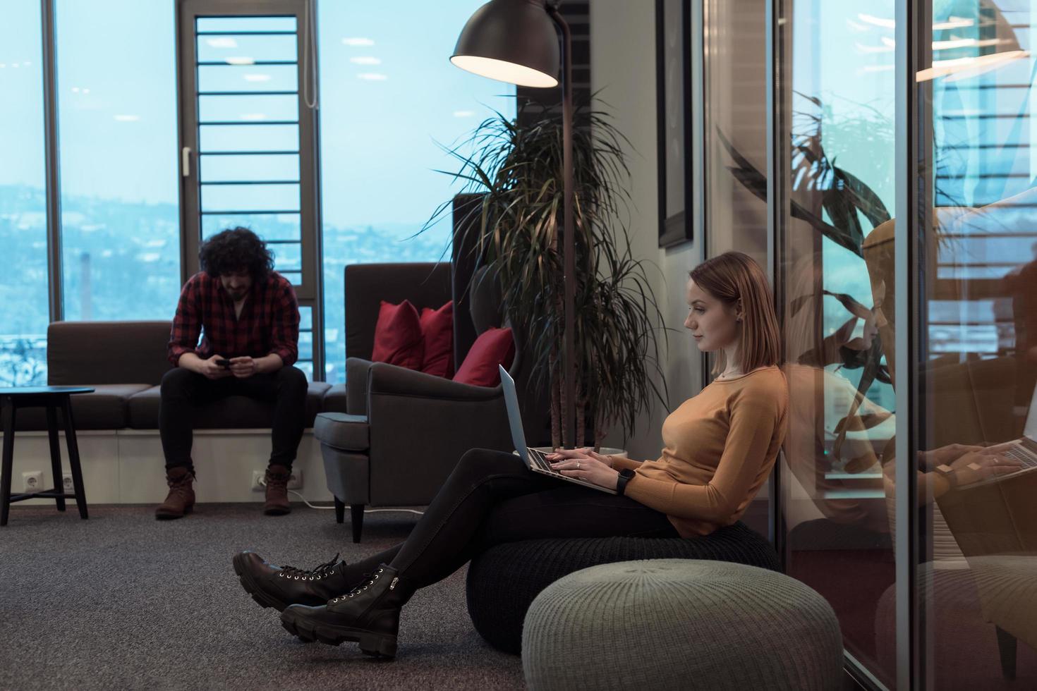 Two business women sitingt in a modern coworking space on a break from work and relax using a laptop. Selective focus photo
