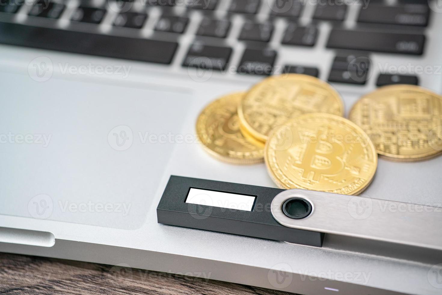 Hardware cryptocurrency wallet with golden Bitcoin BTC on computer. Safe storage for crypto. photo