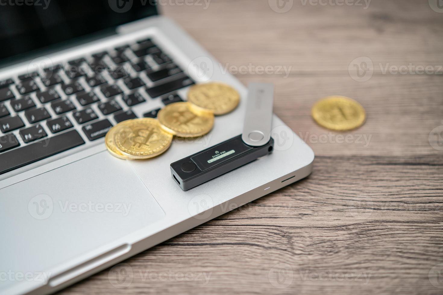 Hardware cryptocurrency wallet with golden Bitcoin BTC on computer. Safe storage for crypto. photo