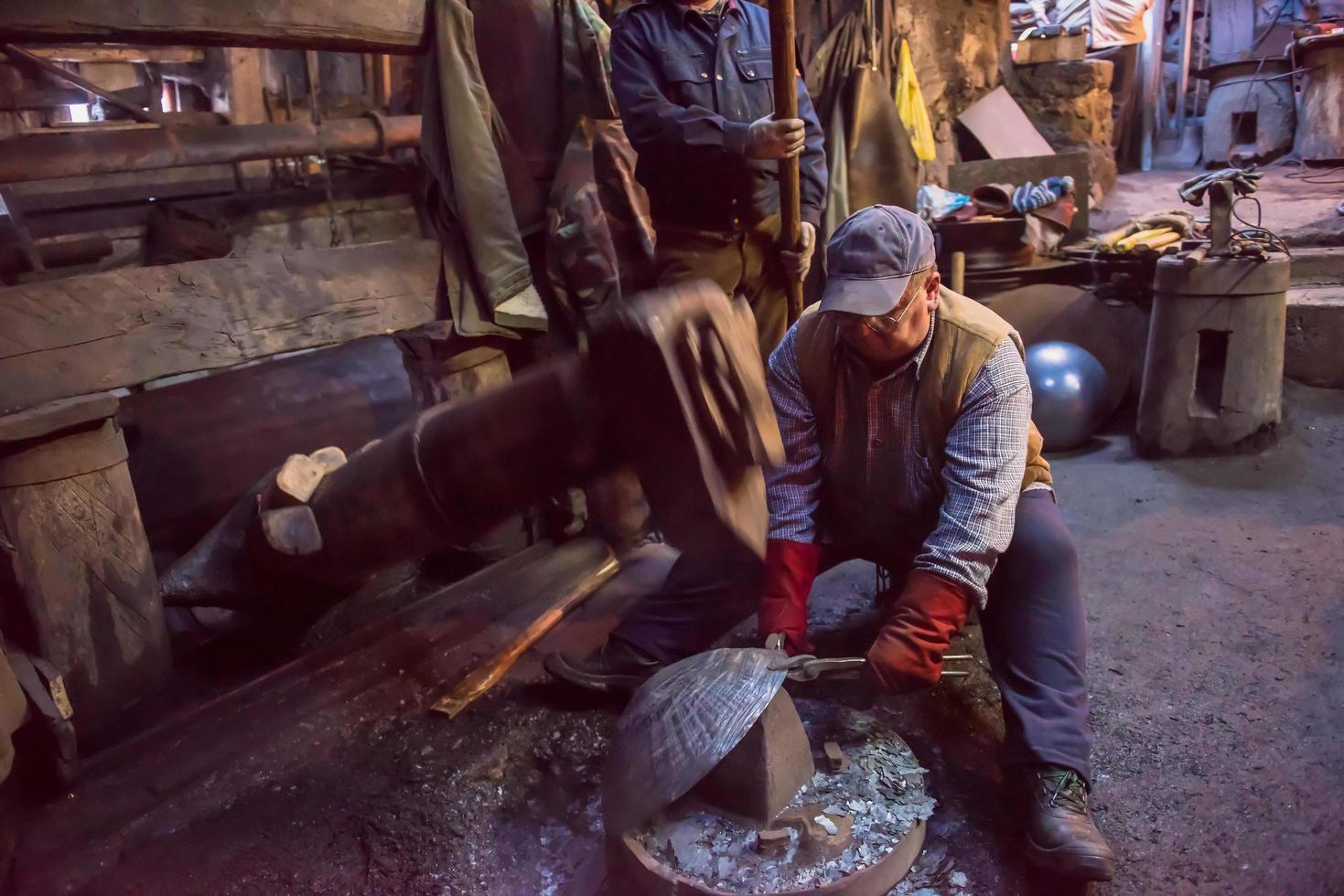 blacksmith workers using mechanical hammer at workshop photo