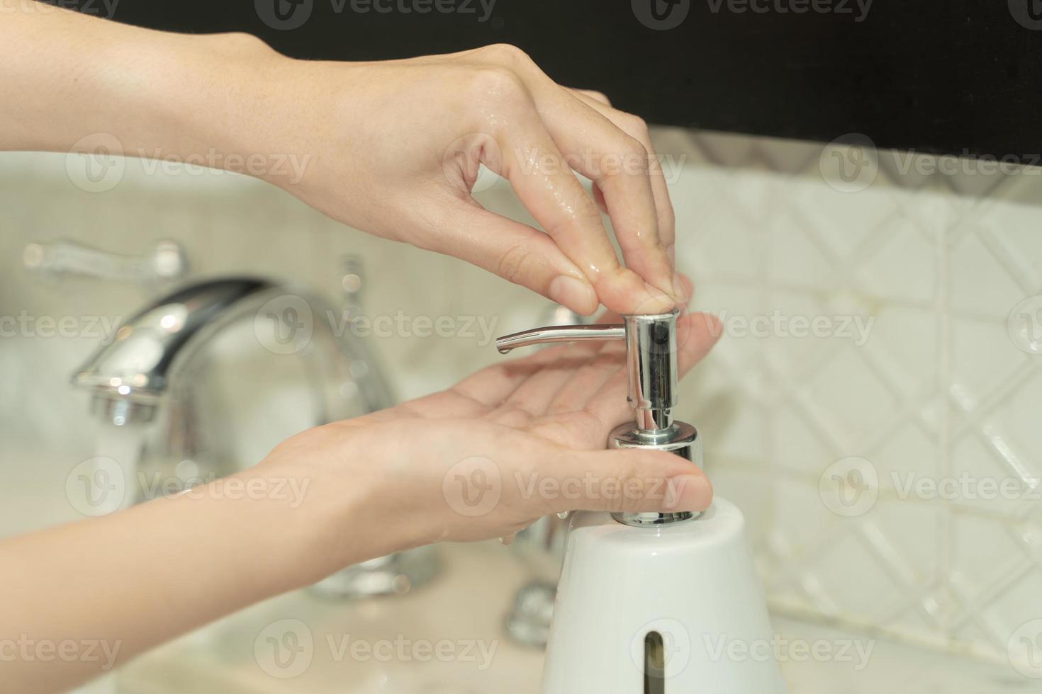 la mano de la mujer usa jabón y se lava bajo el grifo de agua. concepto de higiene. foto
