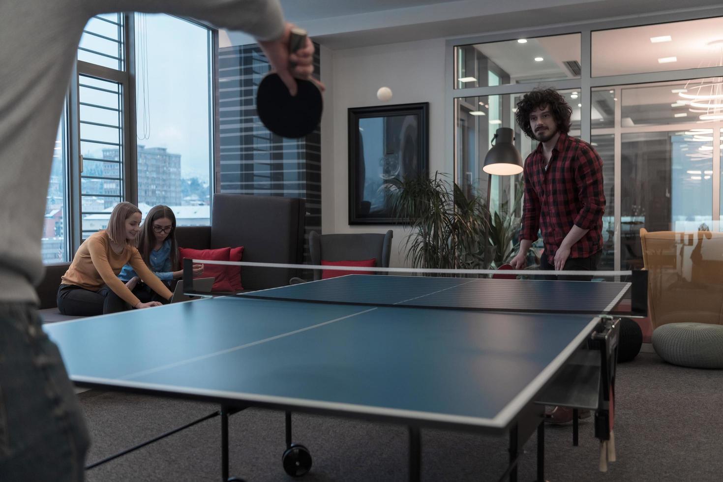 Two young start up business man playing ping pong tennis at modern creative office space people group have meeting and brainstorming in background photo