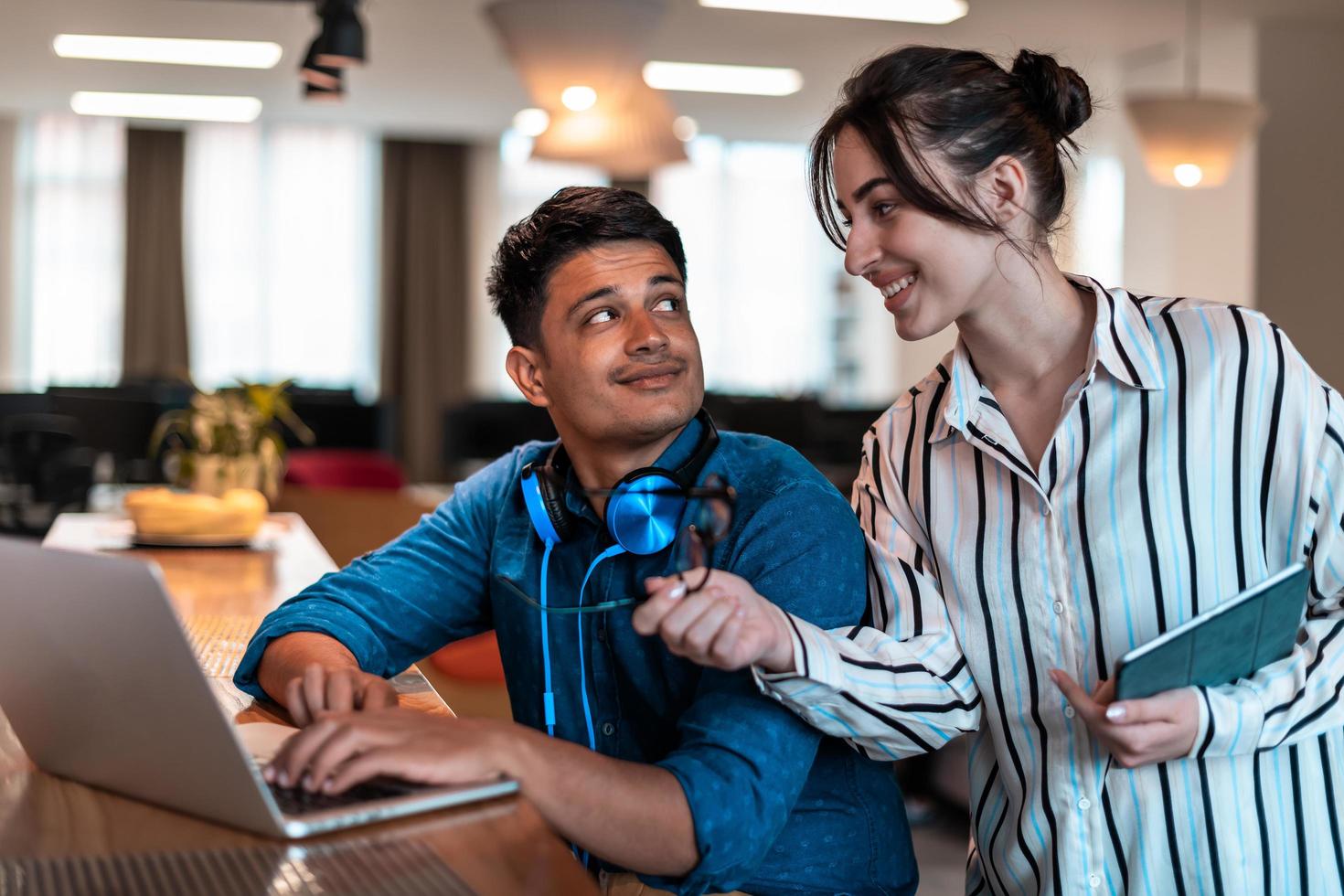 Multiethnic business people man with a female colleague working together on tablet and laptop computer in relaxation area of modern startup office photo