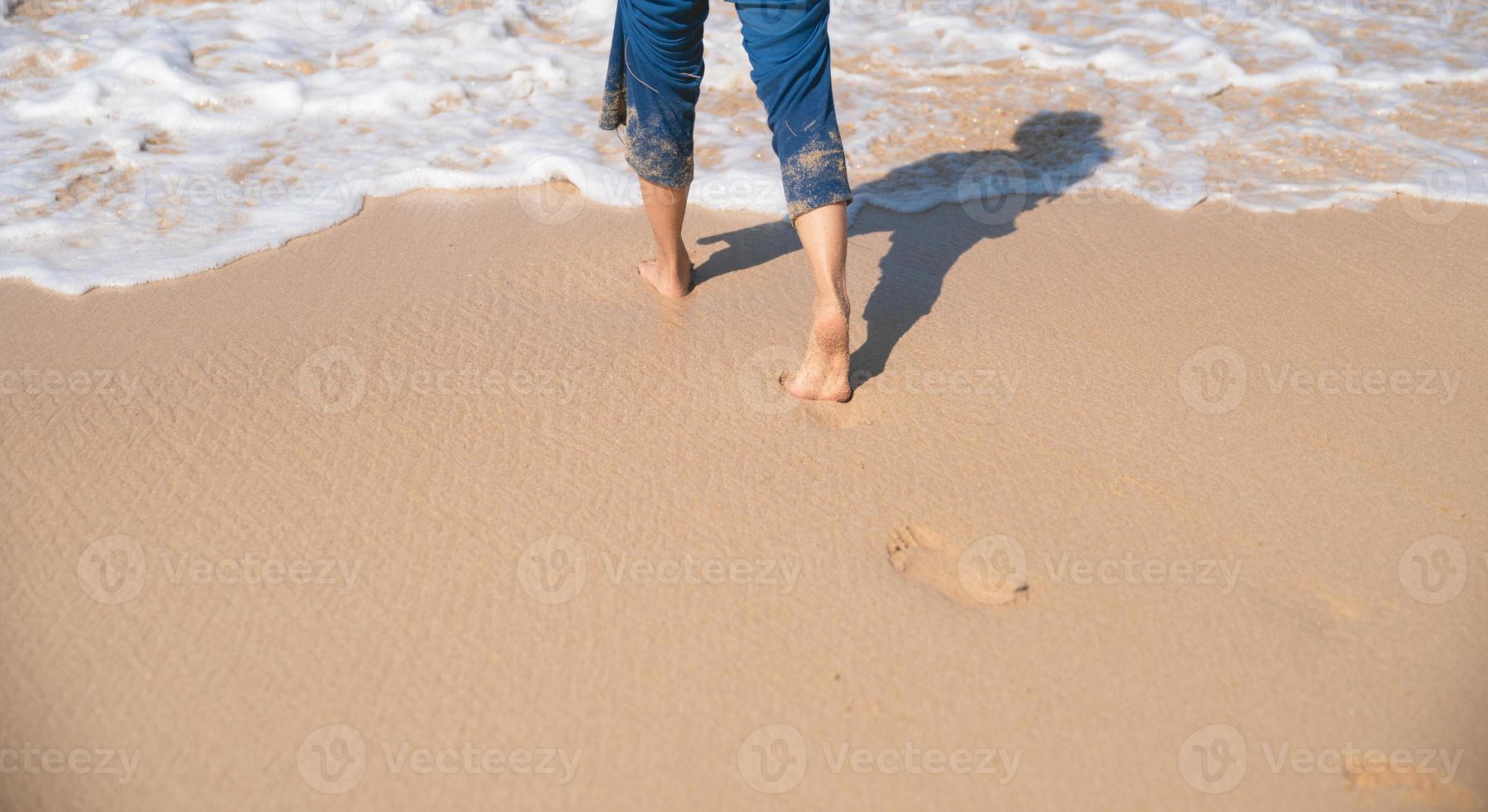 Footprints in the sand on the beach. Woman walking to the sea. photo