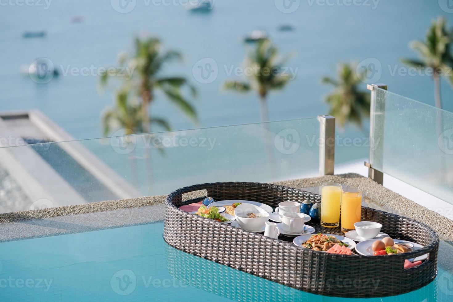Breakfast set in tray in swimming pool, floating breakfast in tropical resort villa with ocean view. photo