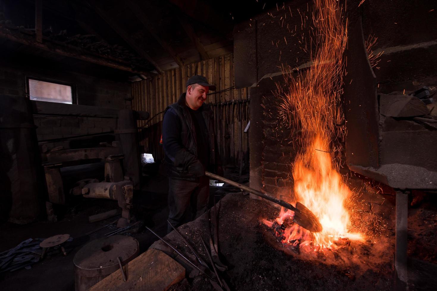 joven herrero tradicional trabajando con fuego abierto foto