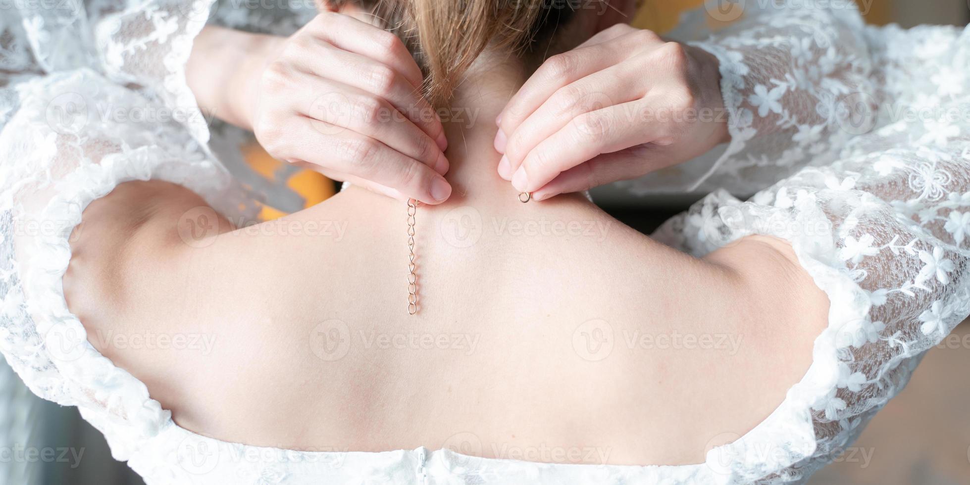 Back side of woman is wearing necklace by her self. photo