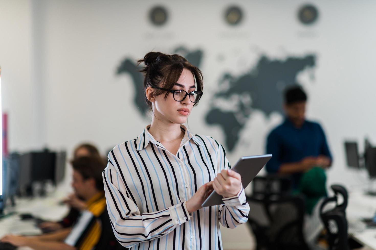 Portrait of businesswoman in casual clothes holding tablet computer at modern startup open plan office interior. Selective focus photo