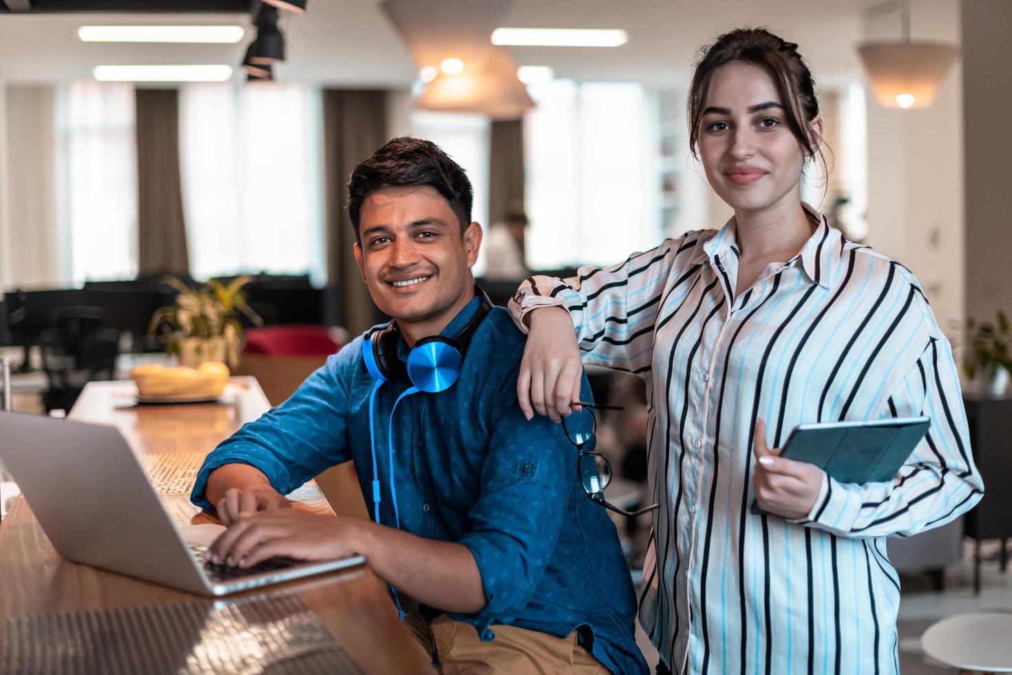 Multiethnic business people man with a female colleague working together on tablet and laptop computer in relaxation area of modern startup office photo