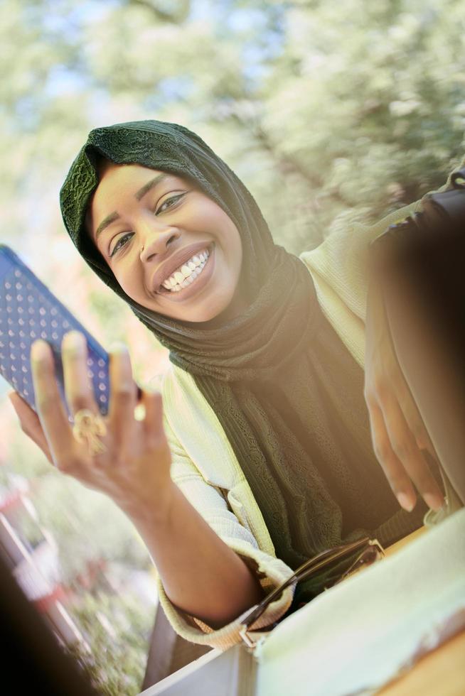 mujer africana que usa un teléfono inteligente con ropa islámica tradicional foto