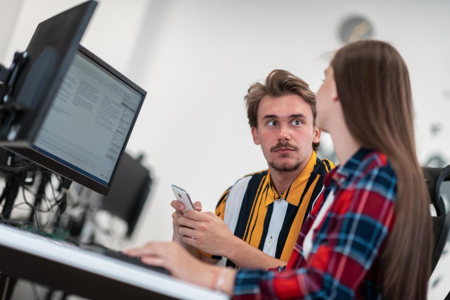 Business couple working together on project using tablet and desktop computer at modern open plan startup office. Selective focus photo
