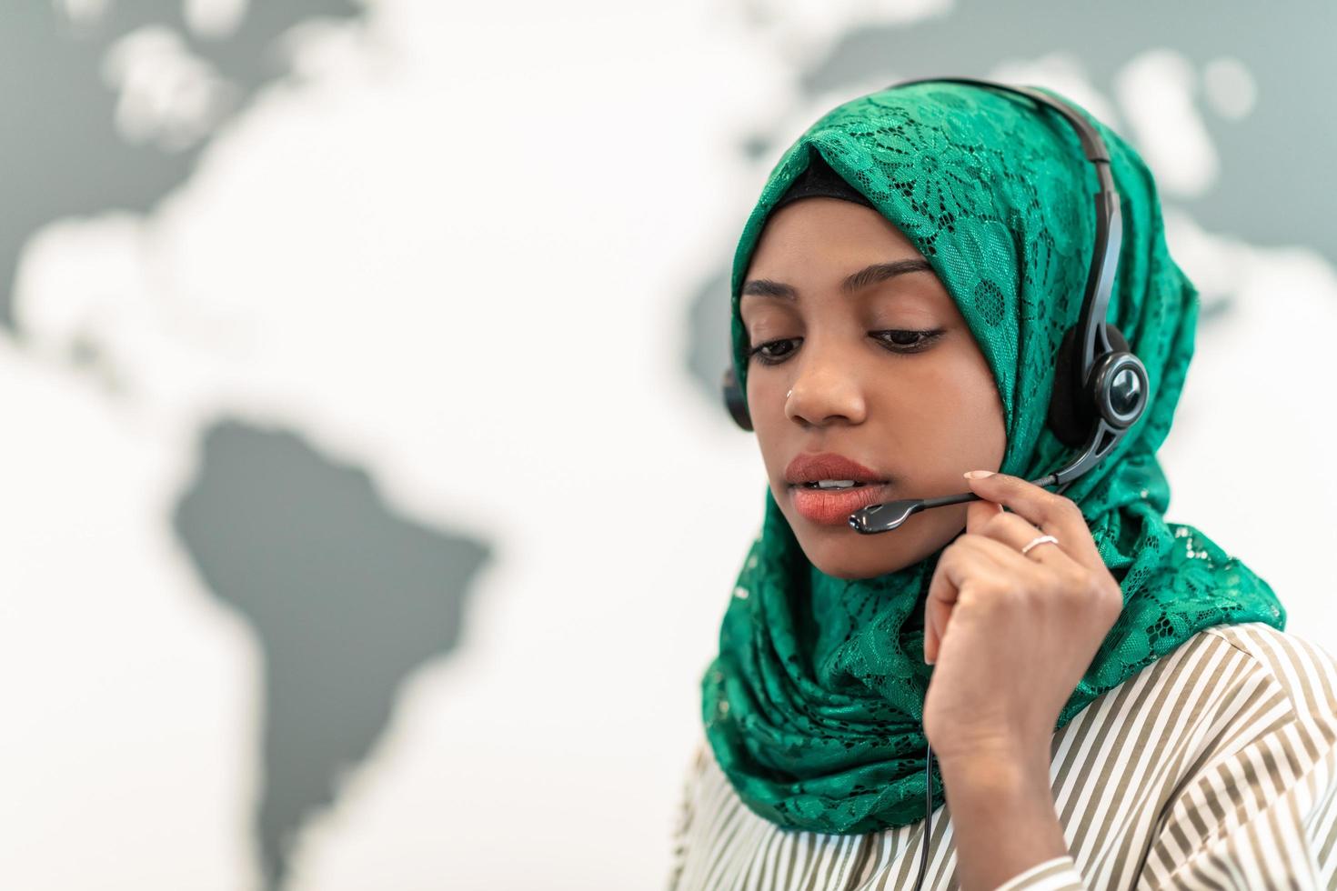 Muslim female with green hijab scarf customer representative business woman with phone headset helping and supporting online with customer in modern call centre photo