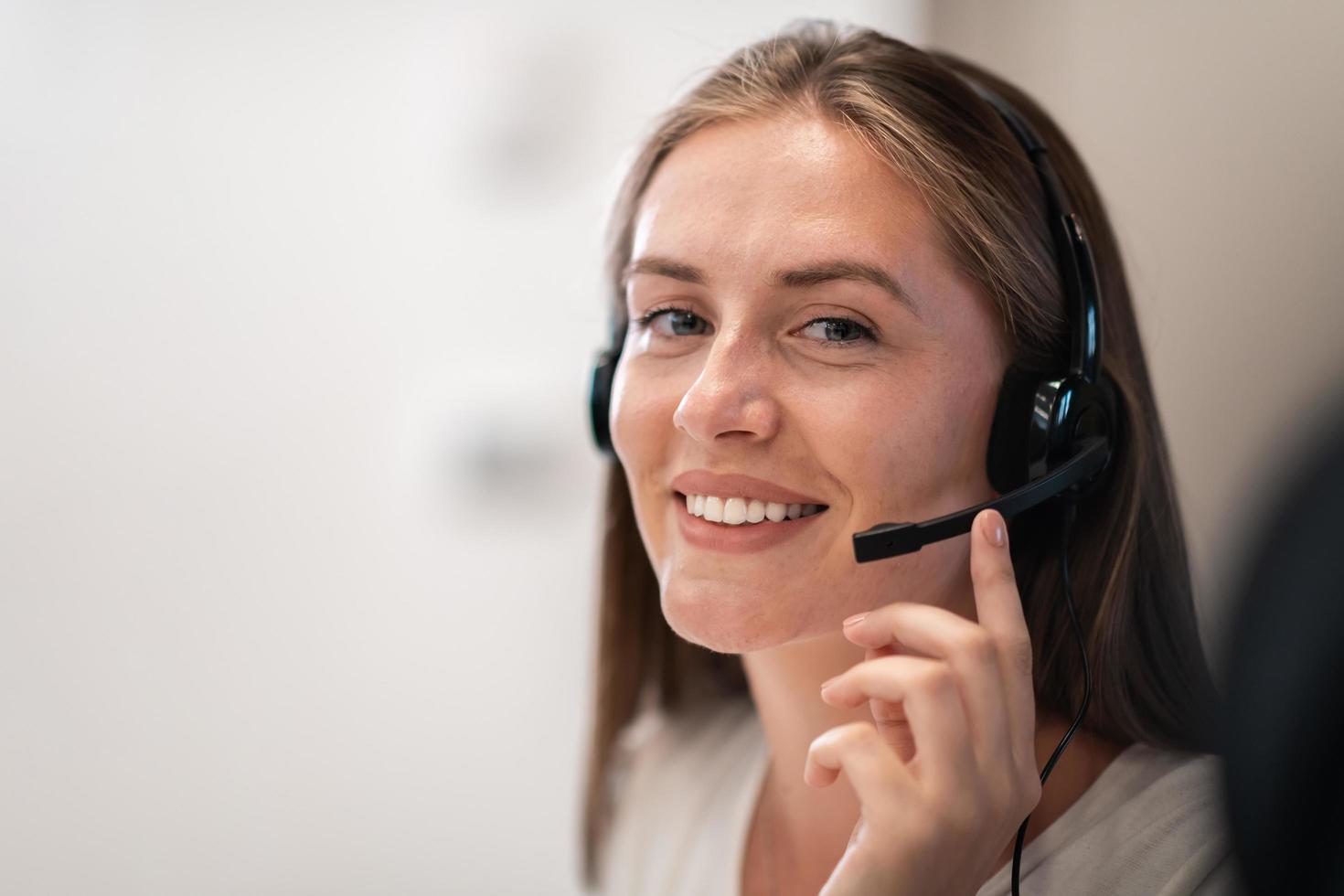 Helpline female operator with headphones in call centre.Business woman with headsets working in a call center. Selective focus photo