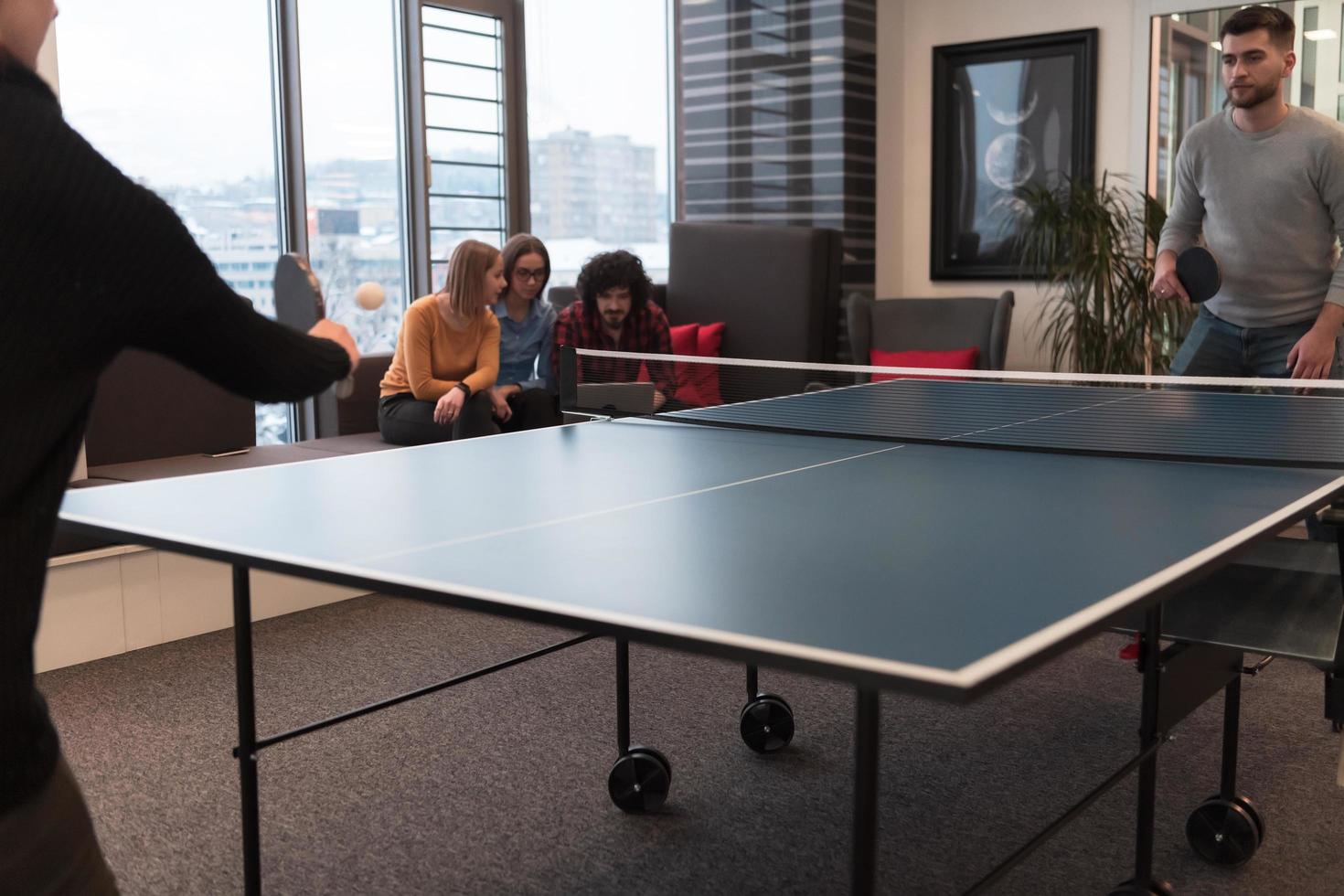 Two young start up business man playing table tennis at modern creative office space people group have meeting and brainstorming in background photo