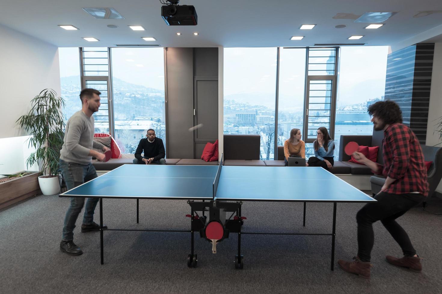 Two young start up business man playing ping pong tennis at modern creative office space people group have meeting and brainstorming in background photo