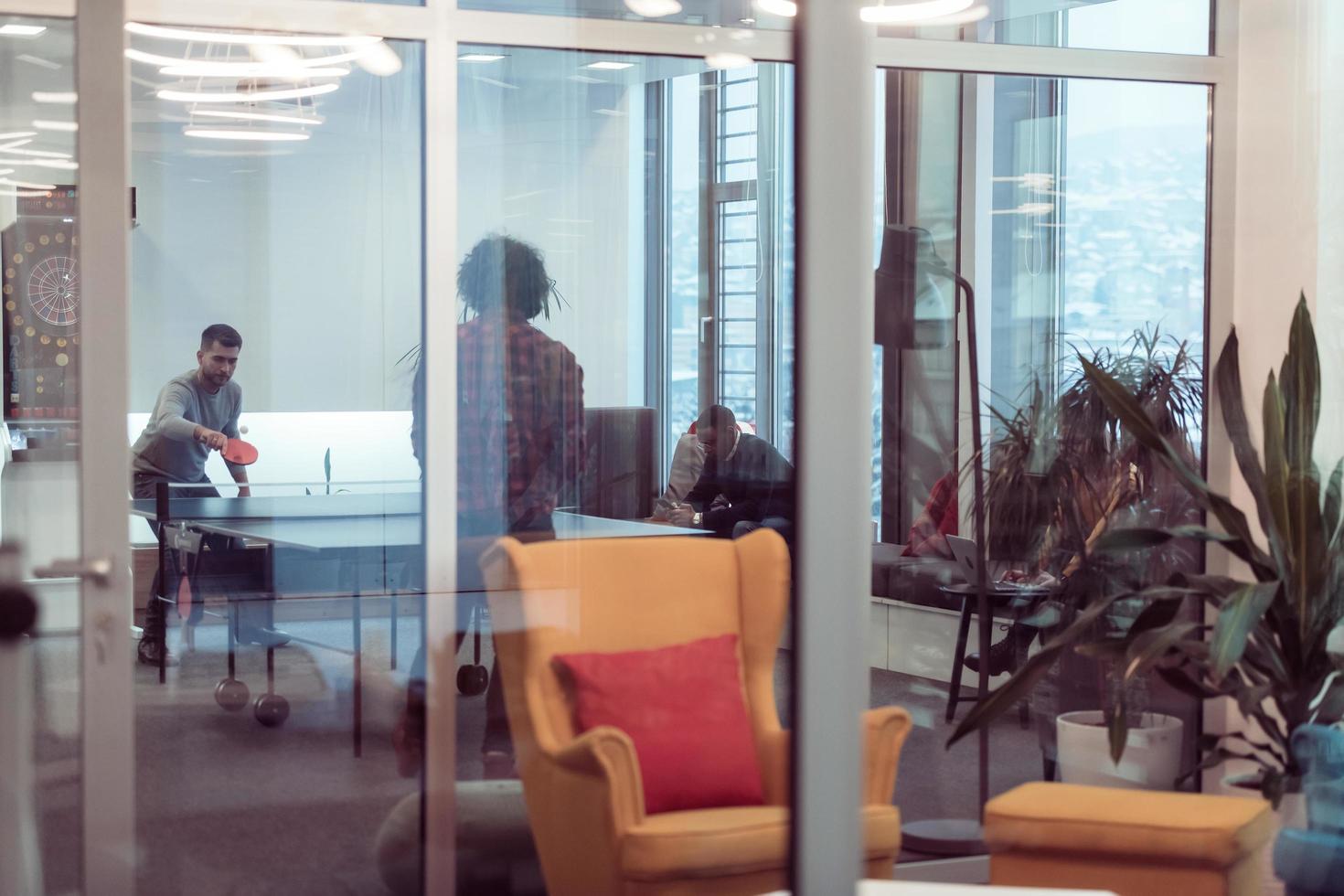 Two young start up business man playing ping pong tennis at modern creative office space people group have meeting and brainstorming in background photo