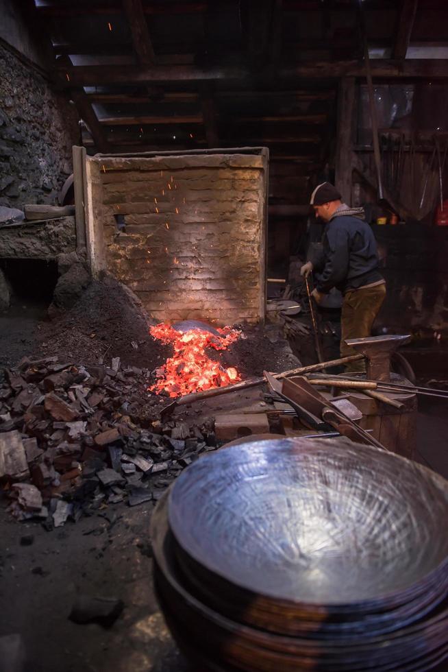 young traditional Blacksmith working with open fire photo